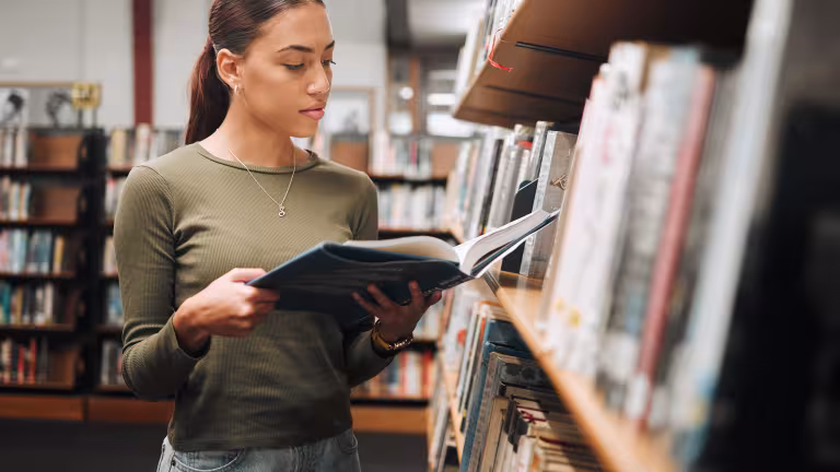 Studente leest boek in bib